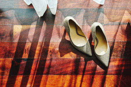 The sun light through curtain, the glittering shoes with shadow on the wooden floorの写真素材