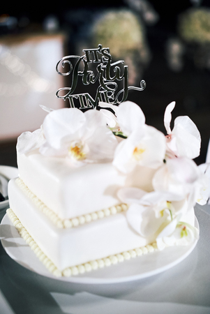 The white wedding cake, 2 layers, decorated with white orchids, with text "it's party time"の写真素材