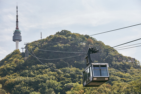 The cable car service from the ground to N Seoul Tower with the mountain in background on the sunny dayの写真素材