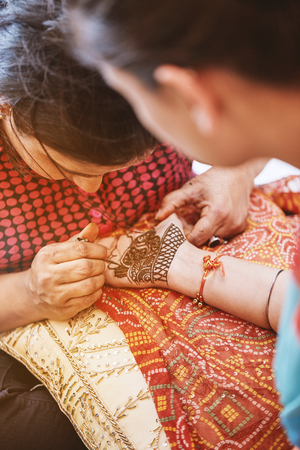 The henna artist (Mehndi) painting the hand of the women who was the guest in the Indian weddingの写真素材