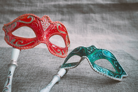 Close up the red and green venetian masquerade, carnival masquerade (Opera mask) with white wood handle on the burlap texture background, Fantasy concept, Photo booth propsの写真素材
