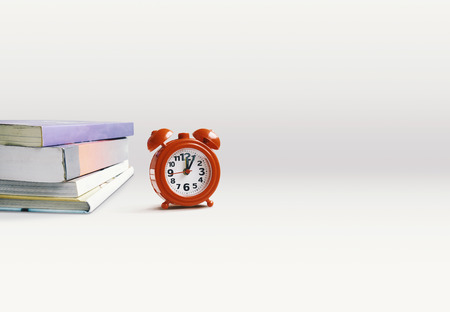 Stacked books with red alarm clock on the white background with copy space. Reading, Education, Lifestyles concept.の写真素材
