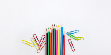 Modern office supplies concepts, Colored crayon pencils and clips on white background with wide banner, brochure, poster design template with copy space. Top view, Closeup.の写真素材