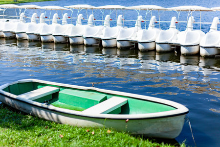 Small fiber glass boats in white and green color floating on the blue water lake in the public park in Bangkok, Thailand on sunny day, Relaxation place for city lifestyles.の写真素材