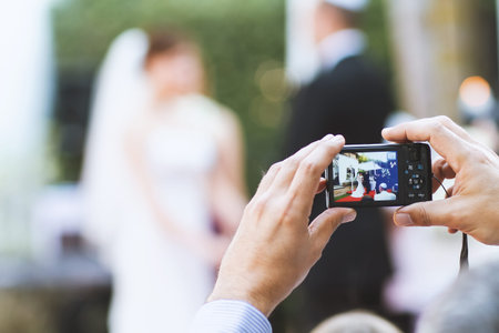 The hand of the guest with a camera take a photo of the bride and groom during the wedding ceremonyの写真素材
