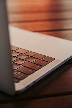 Keys of a laptop in an outdoor on a wooden table at sunset.