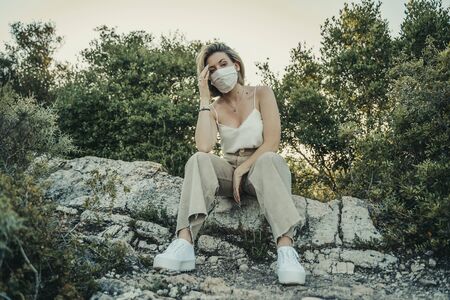 Blonde masked girl in nature landscape during the pandemic.の写真素材