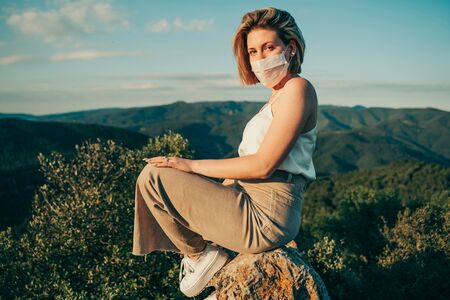 Blonde masked girl in nature landscape during the pandemic.の写真素材