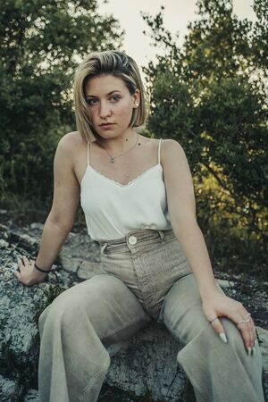 Blonde cute girl in nature landscape with orange and green flowers.の写真素材