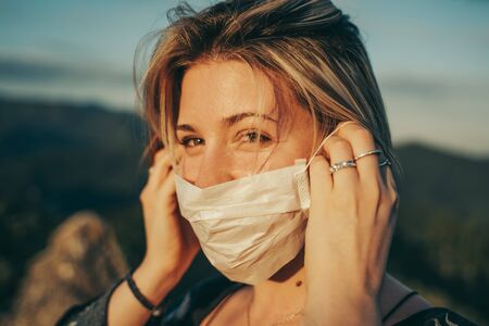 Blonde masked girl in nature landscape during the pandemic.の写真素材