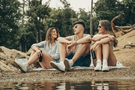 Three young friends having a picnic in the middle of nature in the forest.の写真素材