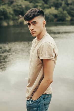 Young boy model on a lake in the middle of the forest in spring season.の写真素材