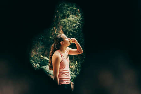 Girl eating an apple through a tree in nature.の写真素材
