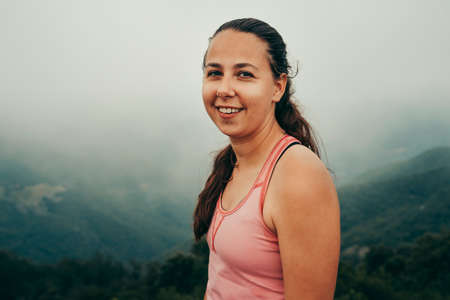 Climber girl smiling on top of a cloudy mountain.の写真素材
