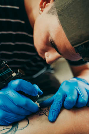Young tattoo artist picking up roll of paper in a tattoo studio.の写真素材