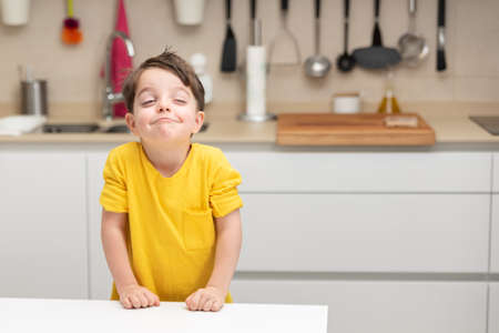 Little boy in yellow shirt in kitchen thinking about what to cookの写真素材
