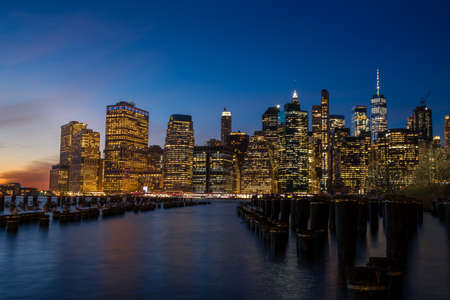 New York from Brooklyn at sunset with dark sky and buildings with lights onの写真素材