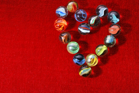 glass marbles on red velvet forming a heart.の写真素材