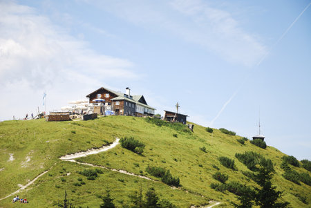 GARMISCH, GERMANY - AUGUST 12. The Wank-Haus on mount Wank in Garmisch, Germany on August 12, 2012. Mountain hut on the 1780m high mount Wank, which can be reached by cable car. People making picnic in the meadow.のeditorial素材