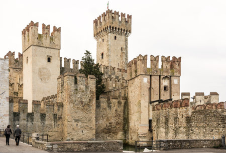 SIRMIONE, ITALY - APRIL 23: Tourists at Scaliger Castle in Sirmione, Italy on April 23, 2014. The castle was built in the 13th century. Foto taken from Piazza Castelloのeditorial素材