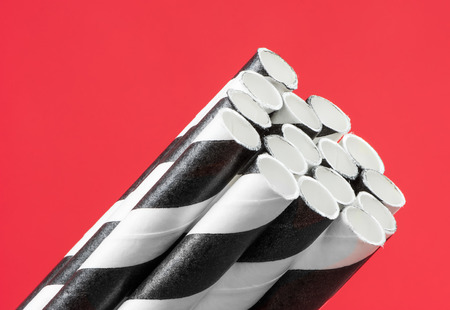 Striped black and white straws on red backgroundの写真素材