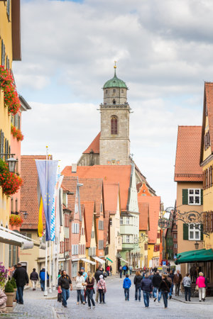 DINKELSBUEHL, GERMANY - SEPTEMBER 27: Tourists in the old town of Dinkelsbuehl, Germany on September 27, 2015. It is one of the best preserved medieaval towns in Germany. Foto taken from Segringer street with view to the minster St. Georg.のeditorial素材