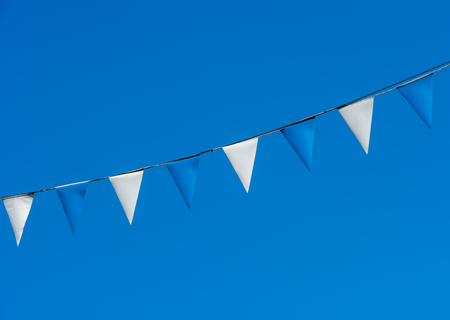 Decoration with blue and white triangular flags against blue skyの写真素材