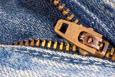 Open zipper of a worn out blue jeans