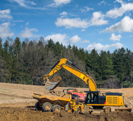 Yellow earth mover filling a lorry at a construction site