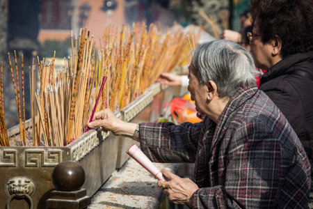 Visitors burn incense sticks and prays at the main altar of Sik Sik Yuen Wong Tai Sin Temple in Hong Kong  It is one of the largest and commemorates the famous monk of yore, Wong Tai Sin  also known as Huang Chu-ping  のeditorial素材