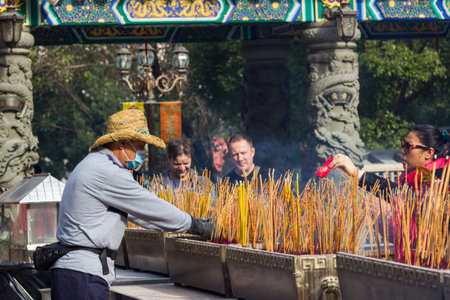 Visitors burn incense sticks and prays at the main altar of Sik Sik Yuen Wong Tai Sin Temple in Hong Kong  It is one of the largest and commemorates the famous monk of yore, Wong Tai Sin  also known as Huang Chu-ping  のeditorial素材