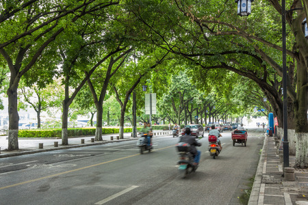 Vehicles moving fast through the shaded streets in Guilin next to Li river.のeditorial素材