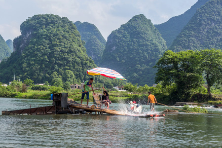 Bamboo rafting in the Yulong River surrounded by dramatic landscape of limestone karst. The rafts are built in the traditional design which is still used by fisherman.のeditorial素材