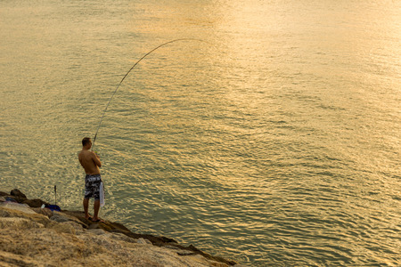 An unidentified person fishing at the rocky shoreline in Sunny Bay Hong Kong.のeditorial素材