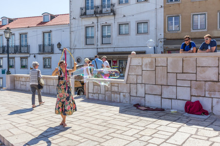 A person entertain the crowd gathered at Lmiradouro Santa Luzia in Lisbon Portugal. Outdoor entertainment is the part of European culture.のeditorial素材