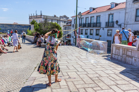 A person entertain the crowd gathered at Lmiradouro Santa Luzia in Lisbon Portugal. Outdoor entertainment is the part of European culture.のeditorial素材
