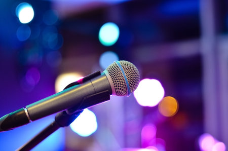 Close-up  of microphone on a defocused  background with multi colored lights at a concert .