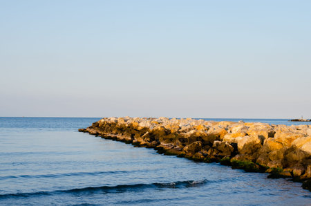 Stones  wave breaker  and  sea against  sunset  blue sky  during summer .