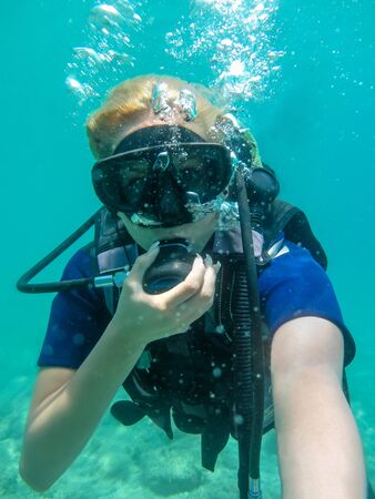 Young caucasian  woman dressed in diving equipment swimming underwater in ionian sea .Greece , Corfu scuba diving in vacation   Women   making selfie underwaterの写真素材