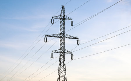 Low angle view of electricity pylon against blue sky at sunset