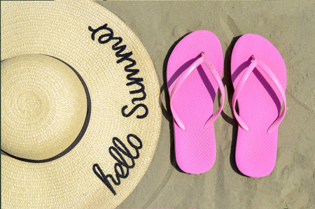 Close-up high angle view of  straw hat with handwritten  text   hello summer  over   and beach swing...