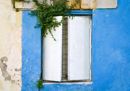 Close-up view of  old rusty  metal window at an old house with painted blue walls .の写真素材