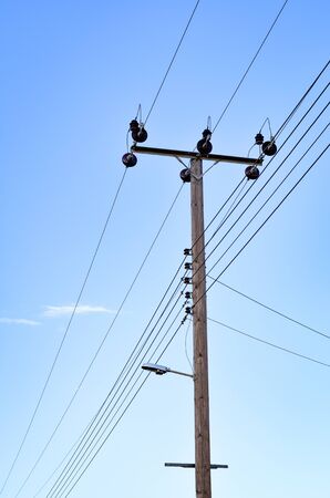Low angle view of  wooden electricity pylon against clear blue sky .の写真素材