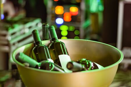Bottles of wine unopened in an stainless steel golden  iron bowl at an  party -event  on a defocused green  lights  background .の写真素材