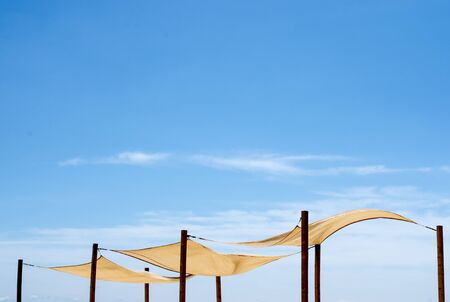 Close-up  of  white canvas roofing for  beach lounge agains blue sky  during summer.の写真素材