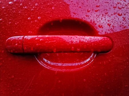 Red car handle  covered with rain dropsの写真素材
