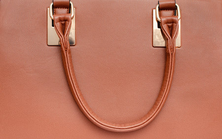 Close-up of brown luxury women leather handbag handle . Top view.