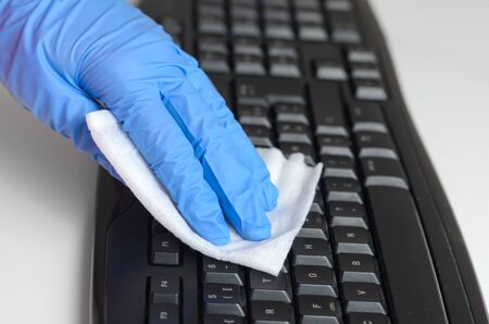 Woman with  gloves cleaning and disinfecting computer keyboard with napkins  Corona virus cleaning and disinfection of your workspace from office  and   home . Stop the spread of coronavirus .の写真素材
