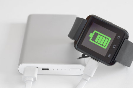 Close-up of  fast external battery that charges a discharged  wearable smartwatch . Fast charging ...