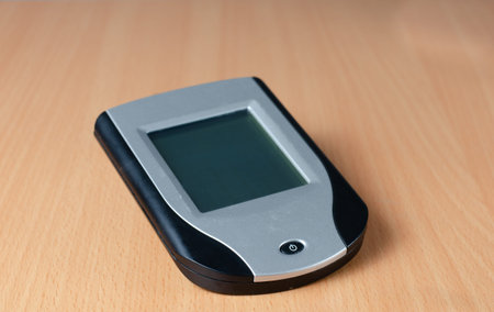Close-up of old touchscreen  personal digital assistent (PDA) on wooden  background , representative...